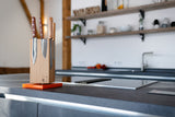Ein bestückter Messerblock mit mehreren Windmühlen Küchenmesser. Im Hintergrund ist eine Design Küche zu sehen.