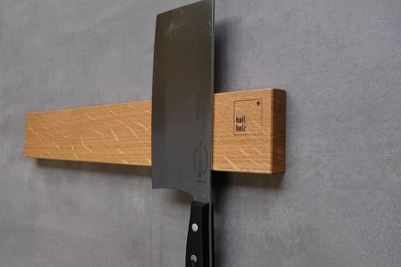 Montierte Holz Messerleiste an einer Betonwand an der ein Messer gehaftet ist.
