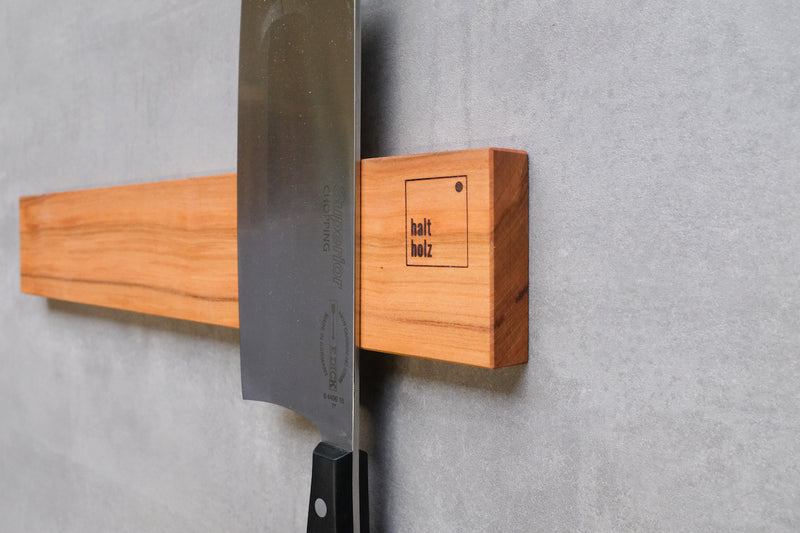 Detailfoto eines Kirschbaum Messerhalter der ein Choppingmesser magnetisch hält. Schräg fotografiert